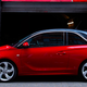 A photo of a red Vauxhall Adam small car parked in front of a brightly-colored wall.